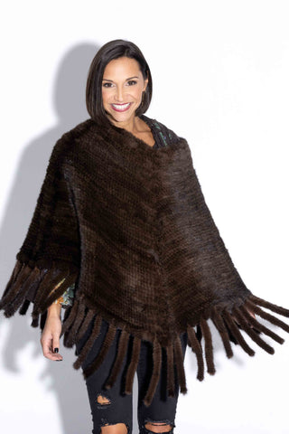 smiling woman wearing a brown knitted mink fur poncho against a white backdrop