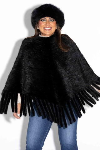smiling woman wearing a ranch knitted mink fur poncho against a white backdrop