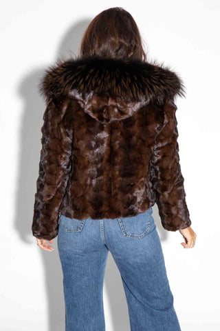 back of woman wearing a brown chevron sectioned mink fur jacket with fox fur trimmed hood against a white backdrop