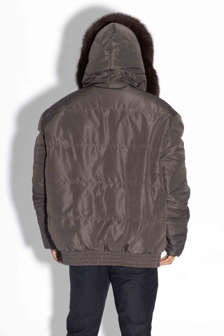 back of man wearing a brown reversible sectioned mink fur jacket with brown fox fur trimmed hood, with brown cloth side facing out, against a white backdrop