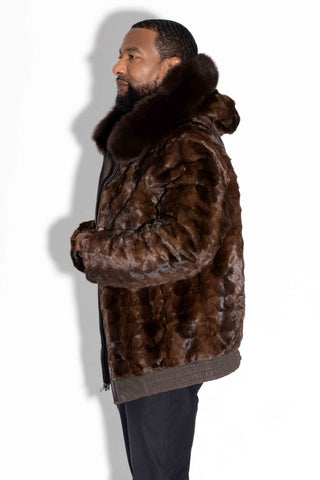side profile of man wearing a brown reversible sheared sectioned mink fur bomber jacket with brown fox fur trim against a white backdrop