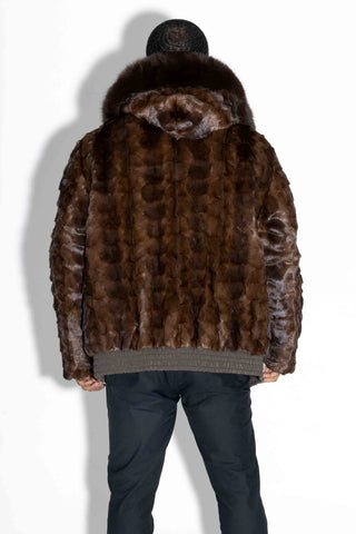 back of man wearing a brown reversible sheared sectioned mink fur bomber with brown fox fur trimmed hood against a white backdrop