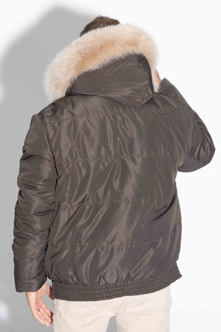 back of man wearing a reversible natural multicolor sectioned mink fur jacket with brown fox fur trimmed hood, with brown cloth side facing out, against a white backdrop