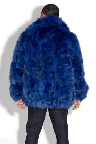 back of man wearing a blue sectioned fox fur bomber jacket against a white background