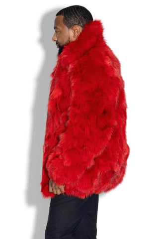 side profile of man wearing a red sectioned fox fur bomber jacket against a white backdrop