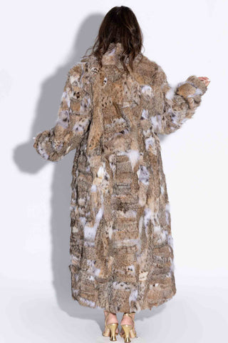 back of woman wearing a sectioned bobcat fur coat against a white backdrop