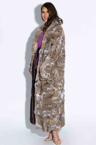 side profile of woman wearing a sectioned bobcat fur coat with shawl collar & bracelet cuffs against a white backdrop