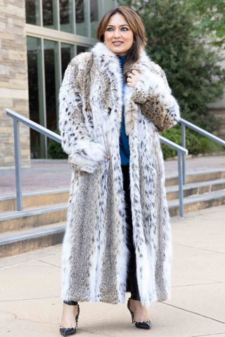 smiling woman wearing a full-length bobcat fur coat on the sidewalk