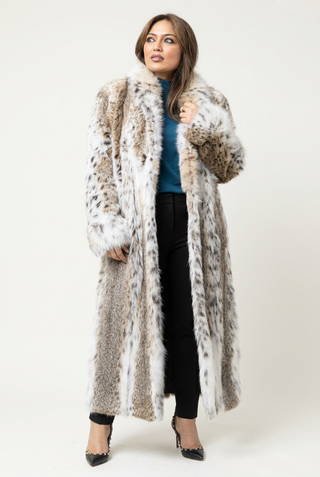 woman wearing a full-length bobcat fur coat against a white backdrop