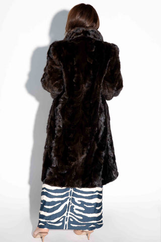 back of woman wearing a brown sheared sectioned mink fur 3/4 coat against a white backdrop