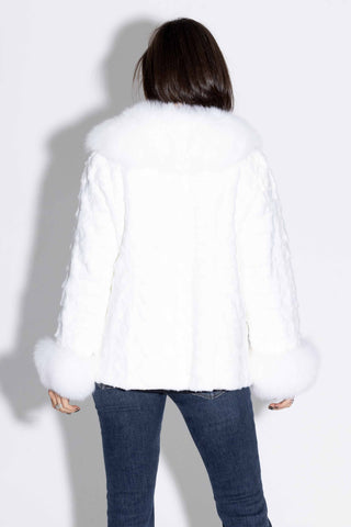 back of woman wearing a white sheared sectioned mink fur jacket with white fox trim against a white backdrop
