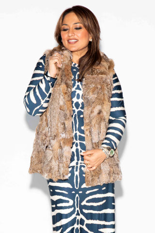 smiling woman wearing a sectioned bobcat fur vest with shawl collar, against a white backdrop