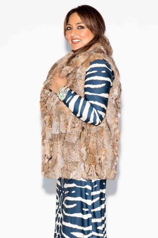 side profile of woman wearing a sectioned bobcat fur vest with shawl collar against a white backdrop