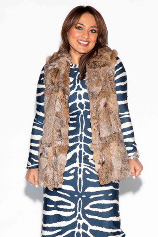 smiling woman wearing a sectioned bobcat fur vest against a white backdrop