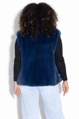back of woman wearing a blue chinchilla fur vest with blue mink fur back against a white backdrop