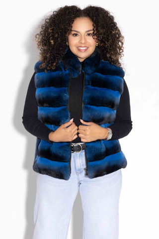 smiling woman wearing a blue chinchilla fur vest with blue mink fur back against a white backdrop
