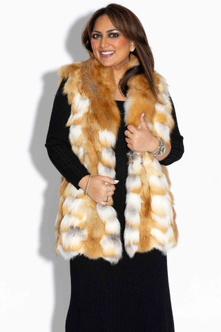 smiling woman wearing a natural red sectioned fox fur vest with shawl collar against a white backdrop