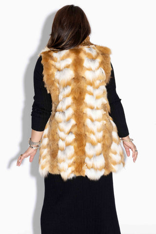 back of woman wearing a natural red sectioned fox fur vest against a white backdrop