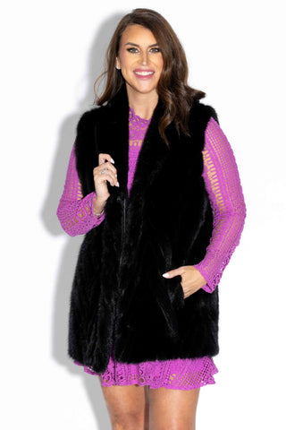 smiling woman wearing a ranch chevron sectioned mink fur vest with shawl collar against a white backdrop