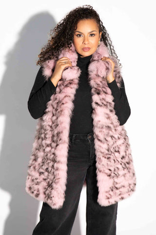 woman wearing a pink and black sectioned fox fur vest with leather inserts against a white backdrop