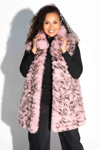 smiling woman wearing a pink and black sectioned fox fur vest with leather inserts