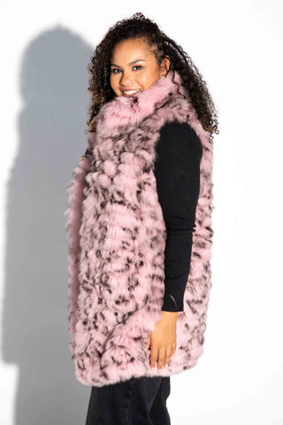 side profile of woman wearing a pink and black sectioned fox fur vest with leather inserts against a white backdrop