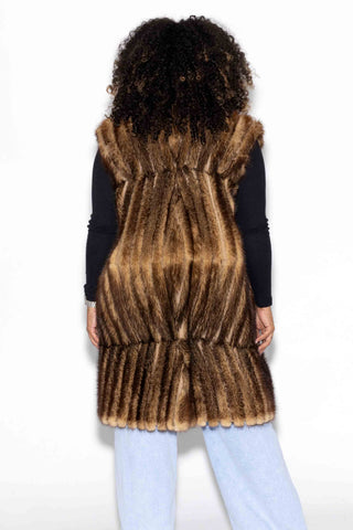 back of woman wearing a long chevron sectioned mink fur vest against a white backdrop