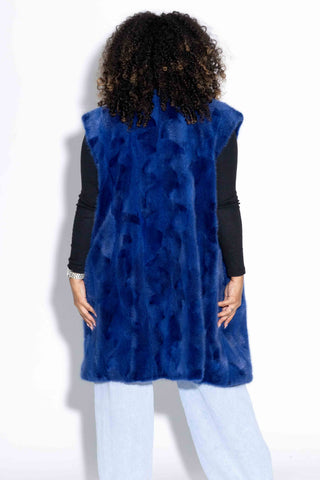 back of woman wearing a royal blue sectioned mink fur vest against a white backdrop