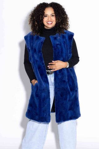 woman wearing a royal blue sectioned mink fur vest, with her hand in the pocket, against a white backdrop
