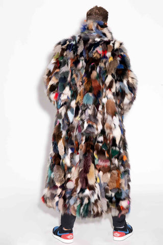 back of man wearing a full length multicolor sectioned fox fur coat against a white backdrop