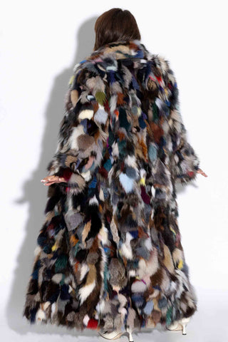 back of woman wearing a full length multicolor sectioned fox fur coat against a white backdrop