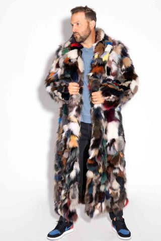 man wearing a full length multicolor sectioned fox fur coat against a white backdrop