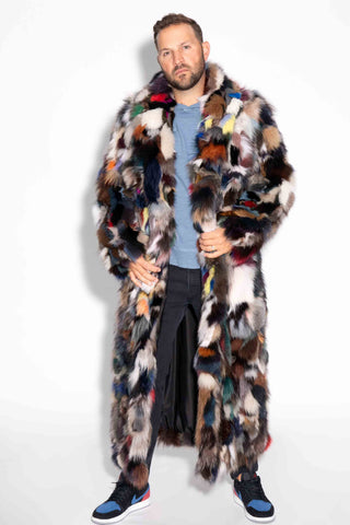man wearing a full length multicolor sectioned fox fur coat against a white backdrop