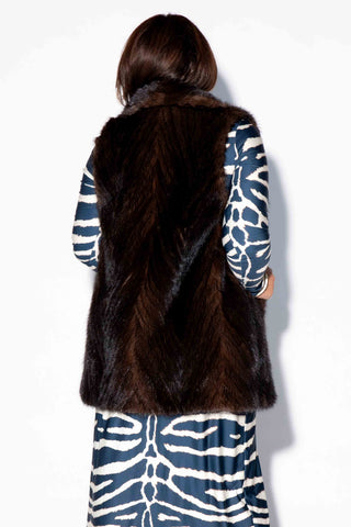 back of woman wearing a mahogany Chevron Sectioned Mink Fur Tails Vest with Shawl Collar against a white backdrop