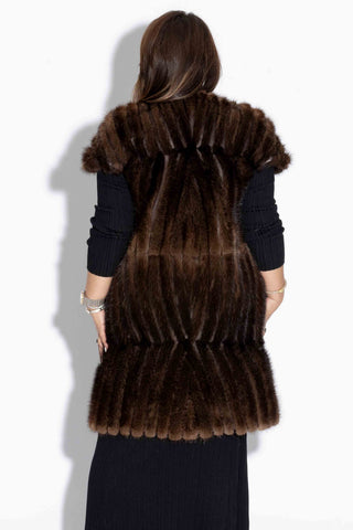 back of woman wearing a long mahogany chevron sectioned mink fur vest with cap sleeves and leather inserts