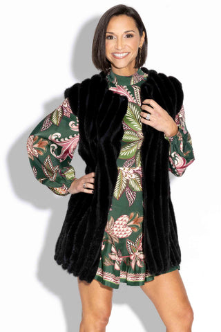 smiling woman wearing a ranch chevron sectioned mink fur vest with leather inserts against a white backdrop