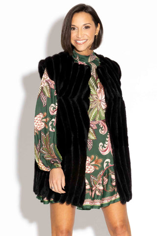 smiling woman wearing ranch chevron sectioned mink fur vest with leather inserts against a white backdrop