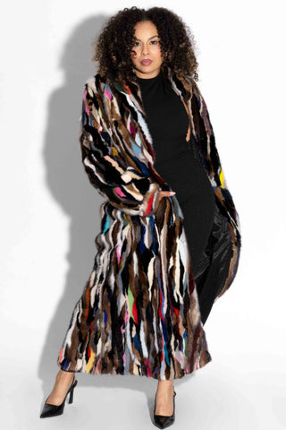 woman wearing a full length multicolor sectioned mink fur coat against a white backdrop