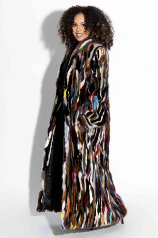side profile of woman wearing a full length multicolor sectioned mink fur coat with shawl collar & bracelet cuffs against a white backdrop