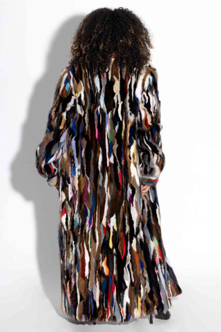back of woman wearing a full length multicolor sectioned mink fur coat against a white backdrop