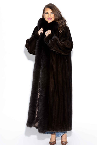 woman wearing a full length mahogany mink fur coat with fox fur tux against a white backdrop