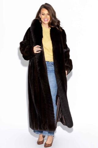 smiling woman wearing a mahogany full length mink fur coat with fox fur tux against a white backdrop
