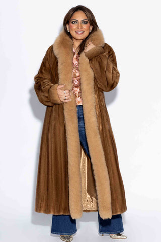 smiling woman wearing a whisky mink fur coat with fox fur tux against a white backdrop