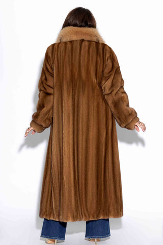 back of woman wearing a full length whisky mink fur coat with fox fur tux against a white backdrop