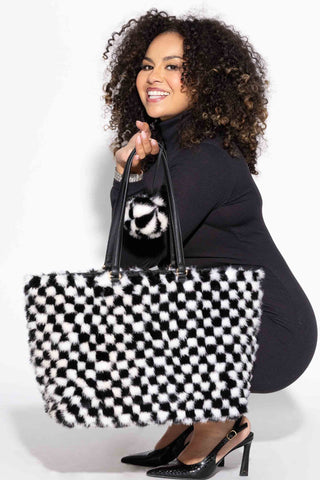 smiling woman holding a ranch and white checkered mink fur purse against a white backdrop