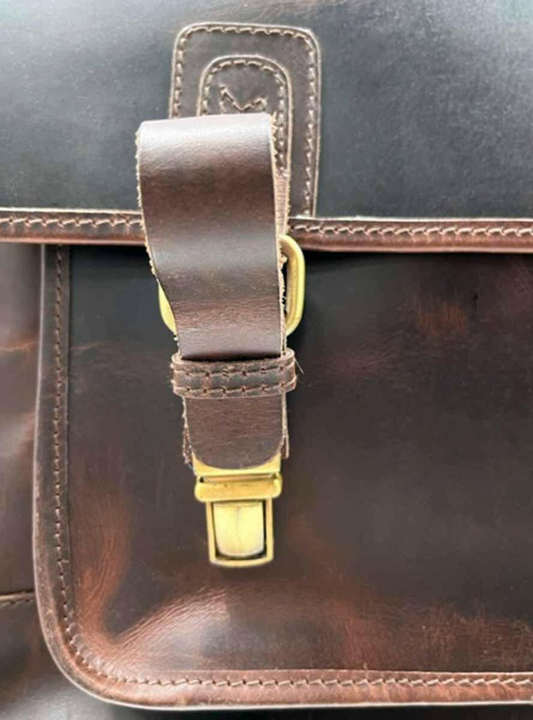 detail of push buckles on dark brown leather messenger bag/briefcase